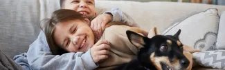 A boy and girl lying on a couch with a dog