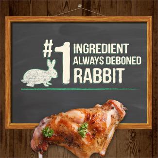 Cooked rabbit in front of a chalkboard that says “#1 ingredient is always deboned rabbit.” 