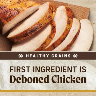 A topdown photo of cooked sliced chicken on a wooden serving board; text below reads "healthy grains. First ingredient is deboned chicken"