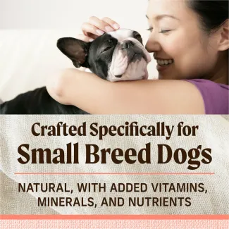 A women smiles while cuddling a Boston Terrier. Below text reads "Crafted specifically for small dog breeds. Natural, with added vitamins, minerals and nutrients"