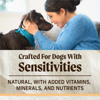 The top of the image shows a woman sitting on the couch holding the head of a brown fluffy dog; text below reads "crafted for dogs with sensitivities. Natural with added vitamins, minerals, and nutrients" 