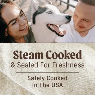 Top of the photo shows a smiling woman and man sitting on either side of a husky. Text below reads "Steam cooked and sealed for freshness. Safely cooked in the USA."